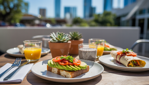 An outdoor breakfast table in Austin with avocado toast, veggie omelet, chia pudding, and burrito.